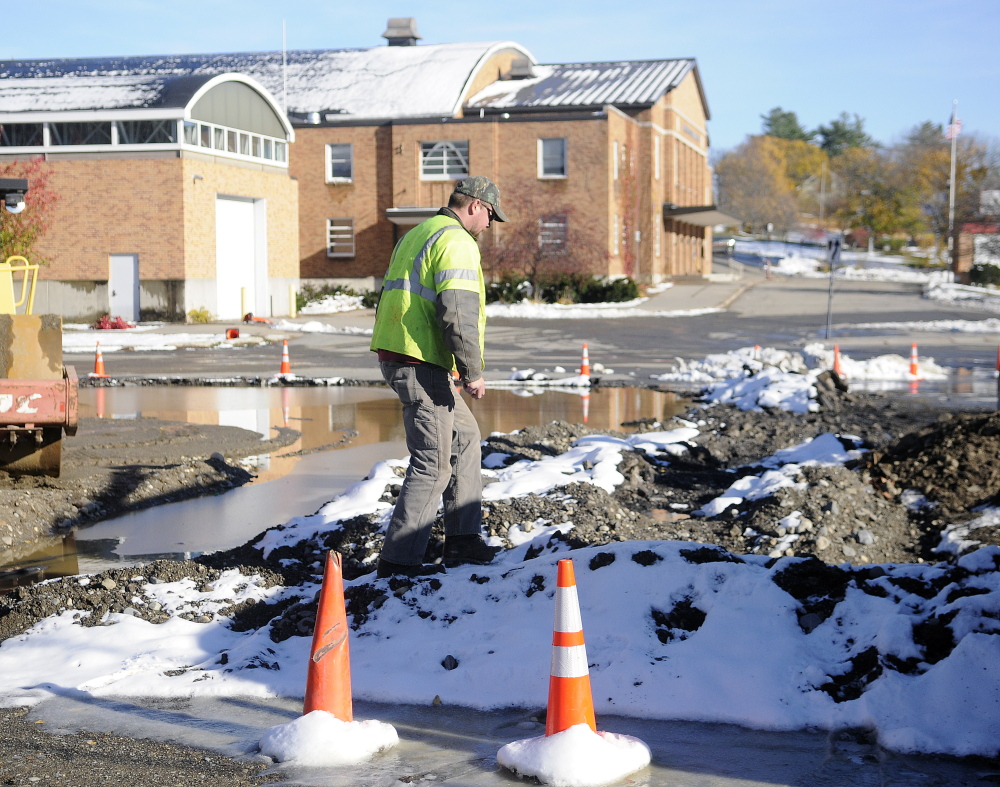 C.H. Stevenson project manager Adam Lake climbs over a pile of soil Monday in the parking lot of the Augusta Armory. The firm planned to pave the parking lot of the polling place but was delayed by Sunday’s storm. The firm plans to grade the lot to provide more than 100 places to park on Election Day.