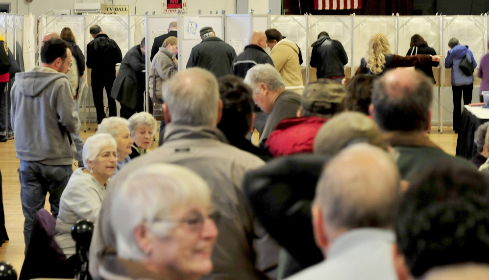 Waterville voters wait in line as others cast ballots during a busy start on Election Day.