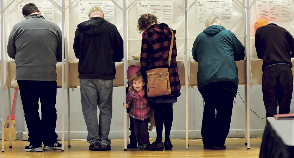 Isla Klepach peers out from a voting booth as her mother, Denise, casts her ballots on Election Day in Waterville.