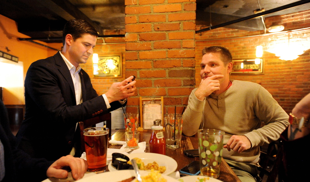 Nick Isgro, Republican candidate for mayor of Waterville, left, checks poll results on his phone while eating dinner with City Councilor  Erik Thomas, D-Ward 4 in downtown Waterville Tuesday night. Isgro was elected mayor while Thomas was defeated in his bid for reelection.