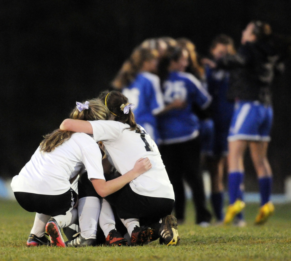 Staff photo by Andy Molloy 
 Maranacook players huddle around each other as Sacopee Valley players celebrate their 1-0 victory in the Western C title game Wednesday in Readfield.