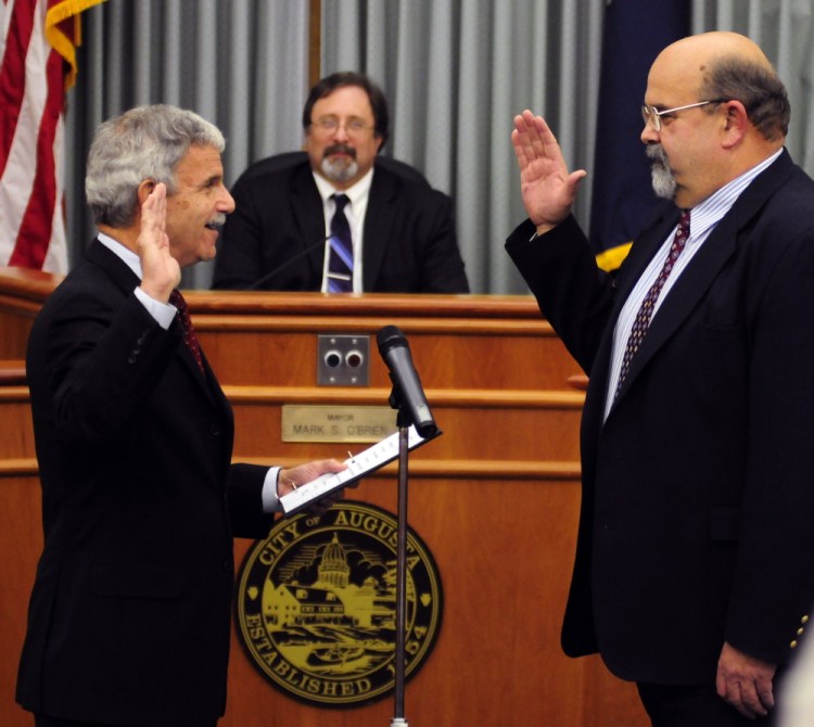 Sen. Roger Katz, left, administers the oath of office Thursday to newly elected Augusta Mayor Dave Rollins at the start of a City Council meeting at Augusta City Center. Outgoing Mayor Mark O’Brien, center, watches the ceremony.