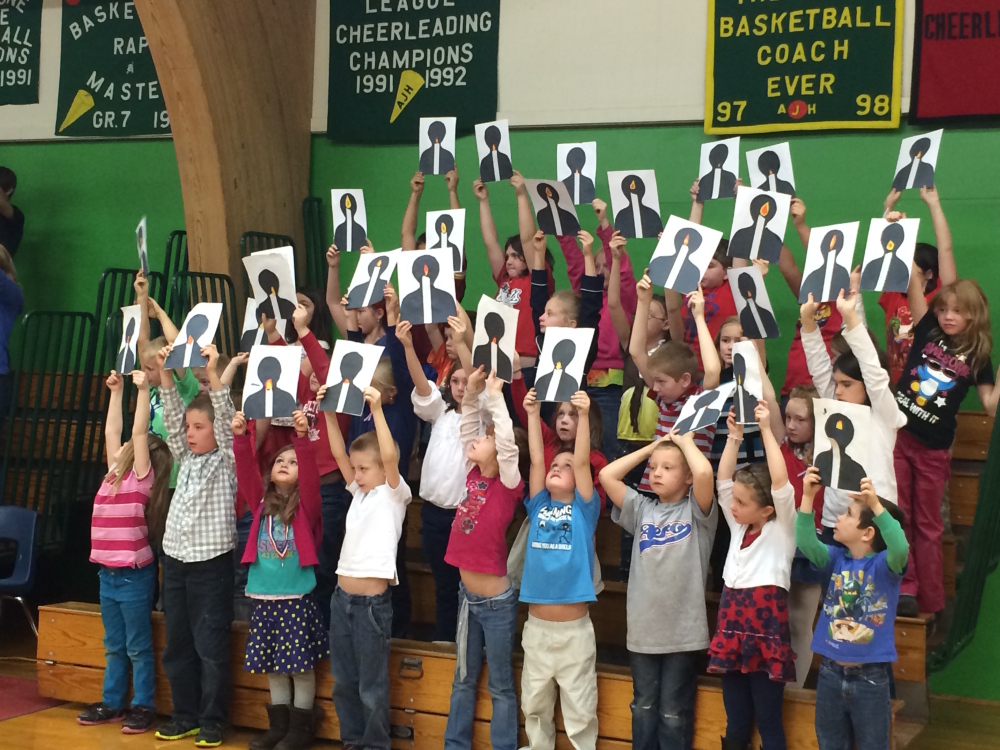 Students at the Athens Community School hold up art work they created in remembrance of military veterans who have died during a Veterans Day celebration at the school on Friday.