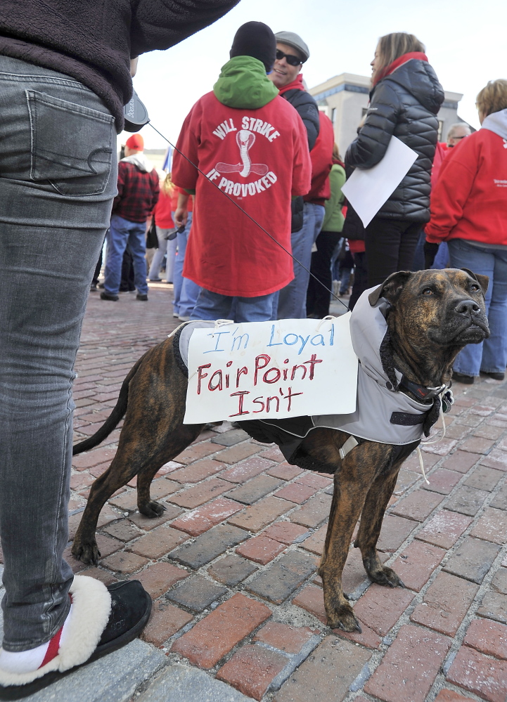 Dixon, a dog owned by Vinalhaven Fairpoint worker Patrick Shane, carries a couple of messages as he attends the striking Fairpoint union workers rally at Monument Square with Andrea Shane, his daughter, on Saturday.