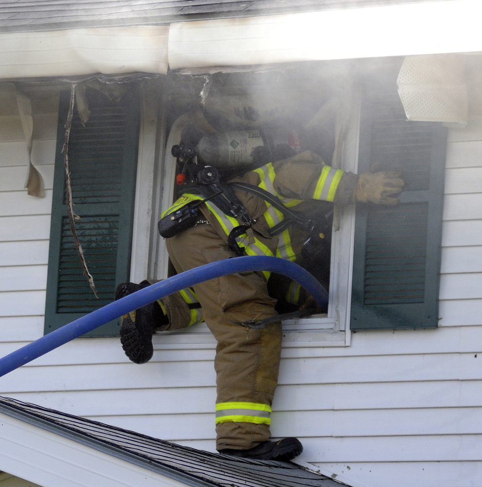 A firefighter climbs through a second floor window into a residence that caught fire in Gardiner on Sunday. Crews from several area communities responded to the blaze that caused extensive interior damage, according to firefighters. No injuries were reported.