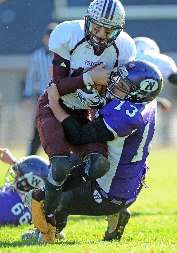 Waterville Senior High School’s Trevor Gray, left, wraps up Foxcroft Academy’s Hunter Smith (10) during the first half last Saturday in Waterville. The Purple Panthers play Winslow this weekend for the Eastern Class C title.
