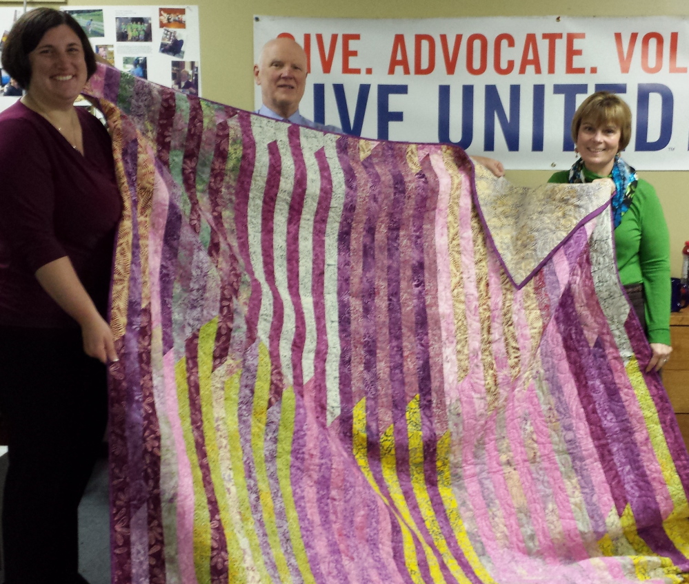 The Great Charity Auction committee members Melissa Caminiti, Bruce Williamson and Wanda Williamson show a quilt donated by committee member Wanda Williamson.