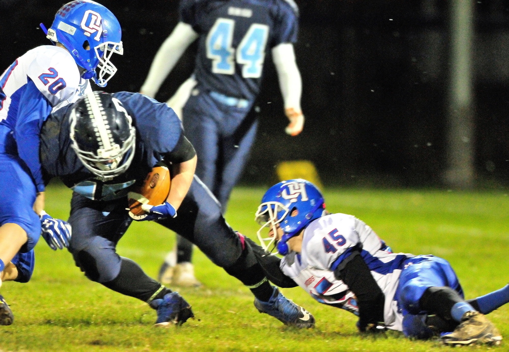 Dirigo fullback Tyler Frost, middle, is tackled by Oak Hill linebacker Levi Buteau, left, and defensive back Kyle Tervo during a Western D semifinal game last Friday.