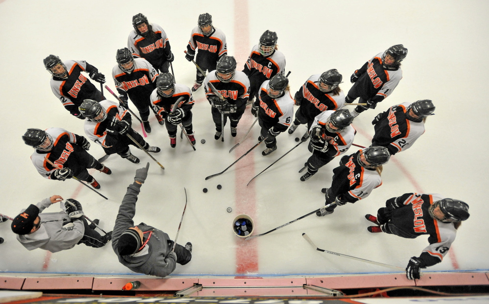 Staff photo by Michael G. Seamans 
 Winslow High School girls hockey coach Chris Downing, bottom left center, instructs his players during practice Thursday at Sukee Arena in Winslow.