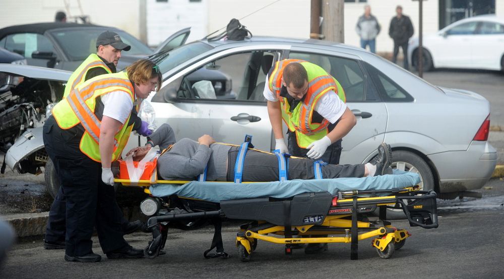Waterville fire department and Delta Ambulance workers secure Heather Wadsworth to a stretcher after extricating her from her car after an accident at the intersection of Oak Street and College Avenue in Waterville on Friday.