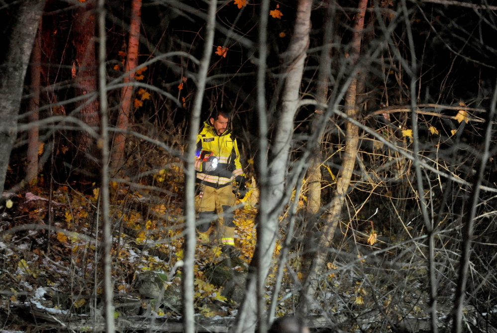 Captain Drew Corey of the Waterville fire department searches the woods for the occupants of a vehicle that crashed Rice Ripps Road near Colby College in Waterville early on Saturday morning