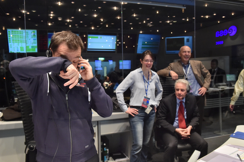Rosetta Flight Director, Andrea Accomazzo,, left,  takes a call after receiving confirmation that the Rosetta mission’s Philae lander has successfully touched down on Comet 67P/Churyumov-Gerasimenko.