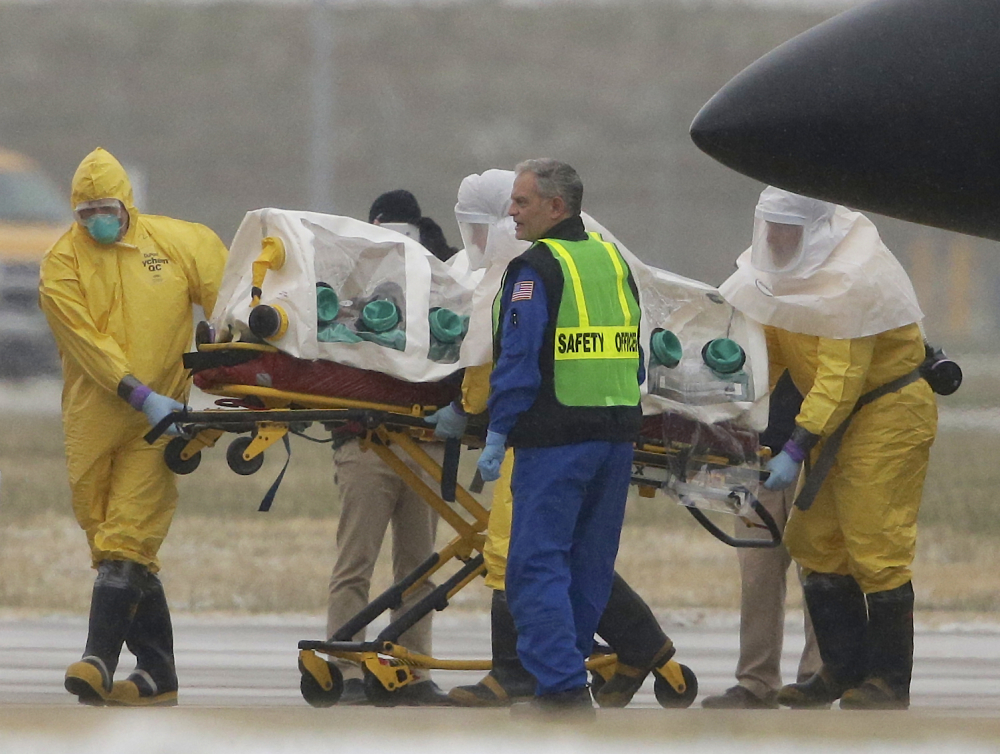 Health workers in protective suits transport Dr. Martin Salia, a surgeon working in Sierra Leone who had been diagnosed with Ebola, from a jet that brought him from Sierra Leone to a waiting ambulance that will take him to the Nebraska Medical Center in Omaha, Neb., Saturday, Nov. 15, 2014.