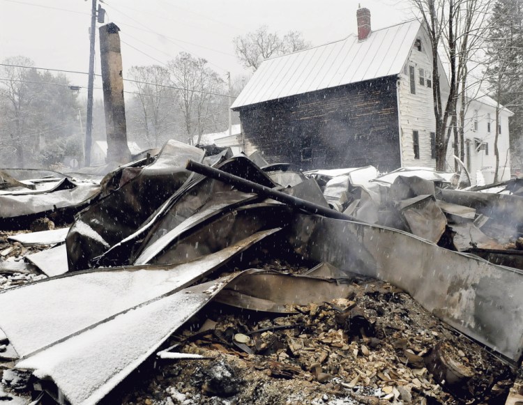 The home of Rick and Tina Belanger lay in blackened ruins in front of the building that housed the Caratunk Post Office and apartments on Monday. Fire broke out Sunday and destroyed the home, another nearby home and garage and did serious damage to the post office property.