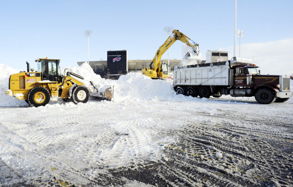 Crews with heavy machinery remove snow outside Ralph Wilson Stadium in Orchard Park, N.Y. on Friday. Snowed out in Buffalo, the Bills are heading to Detroit to play their “home” NFL football game against the New York Jets on Monday night.