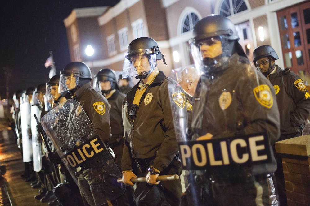Police stand guard during a demonstration outside the Ferguson Police Department on Sunday in Ferguson, Mo. Ferguson and the St. Louis region are on edge in anticipation of the announcement by a grand jury whether to criminally charge Officer Darren Wilson in the killing of 18-year-old Michael Brown.