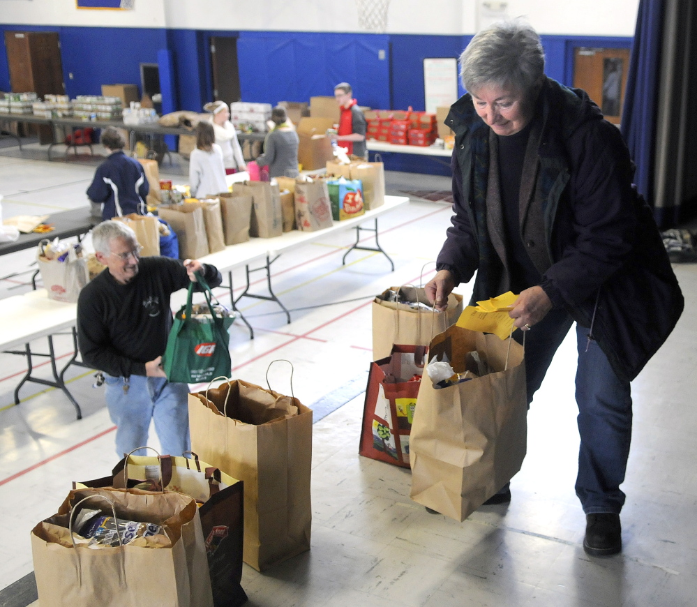 Judge Rae Ann French organizes food baskets Sunday on the stage of St. Michael School that her husband, Fern LaRochelle, left, helped pack. The couple have been helping prepare Thanksgiving baskets at the Augusta school for several years.