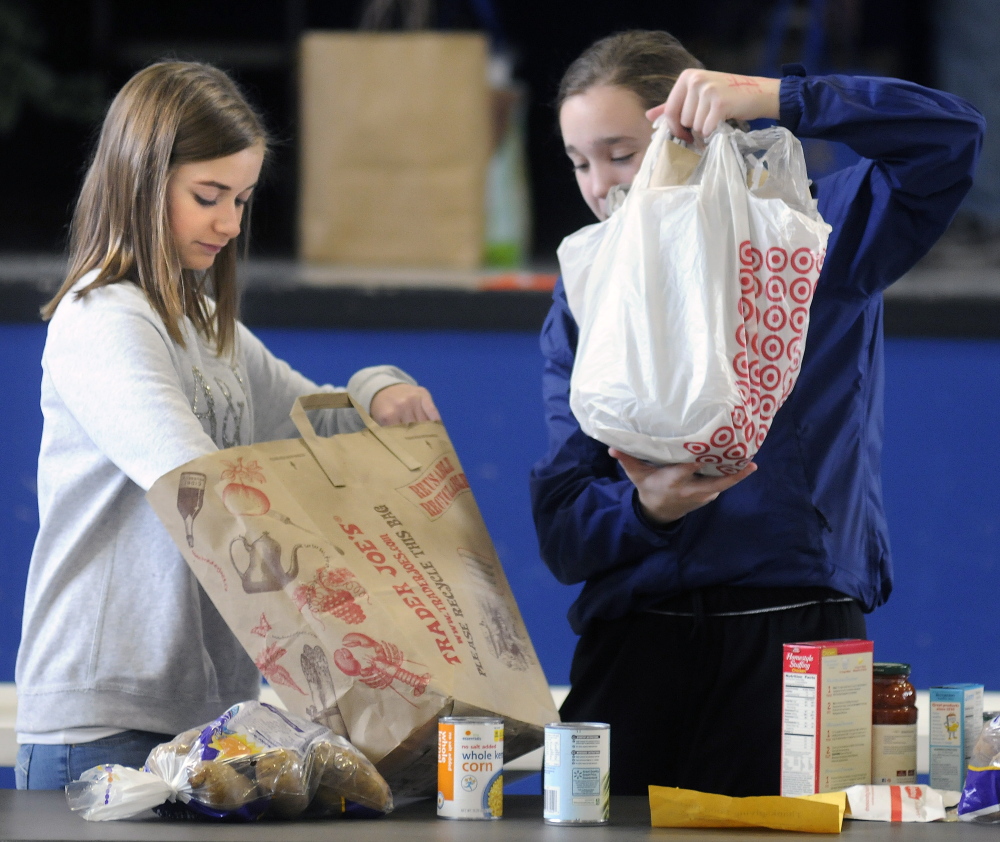 St. Michael School students Leah Allee, 13, right, and Madelyn Rancourt, 14, pack SThanksgiving baskets Sunday at the Augusta school.