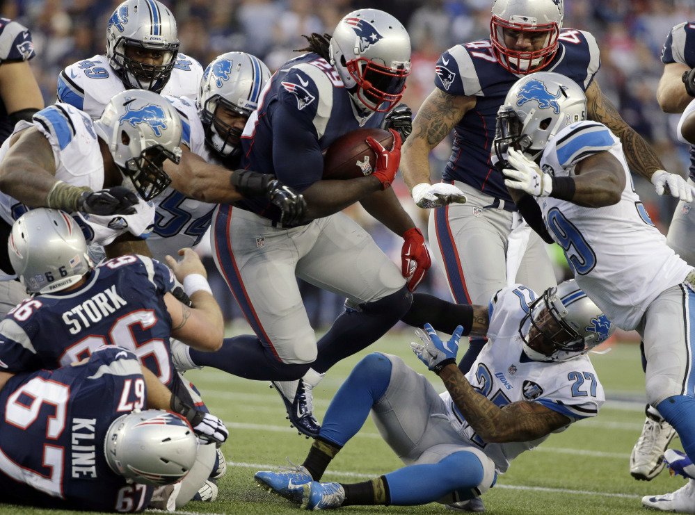 New England Patriots running back LeGarrette Blount, center, runs over Detroit Lions free safety Glover Quin (27) in the second half Sunday in Foxborough, Mass. Blount scored two touchdowns and the Patriots won 34-9.