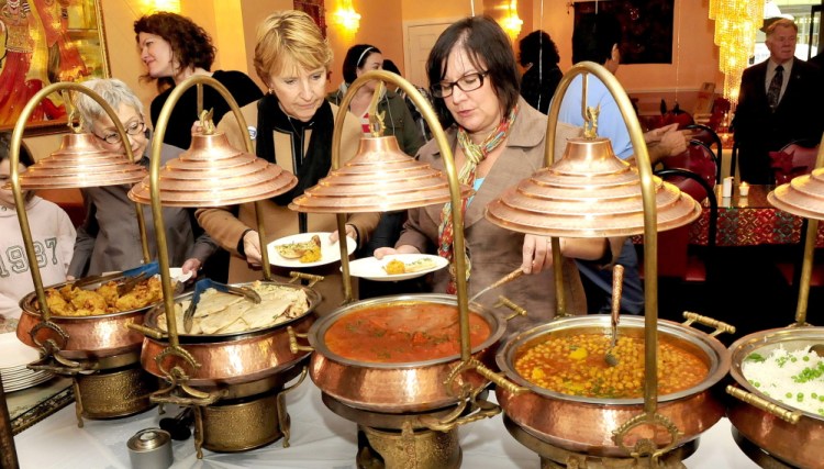 Staff photo by David Leaming
June L’Heureux, left, and Jennifer Olsen of the Waterville Main Street organization sample dishes served during an opening at the Jewel of India restaurant in Waterville on Monday. Local business leaders say the addition of a  restaurant featuring Indian cusine helps to fill out the menu choices available in the city, and help make Waterville a destination spot for people in central Maine.