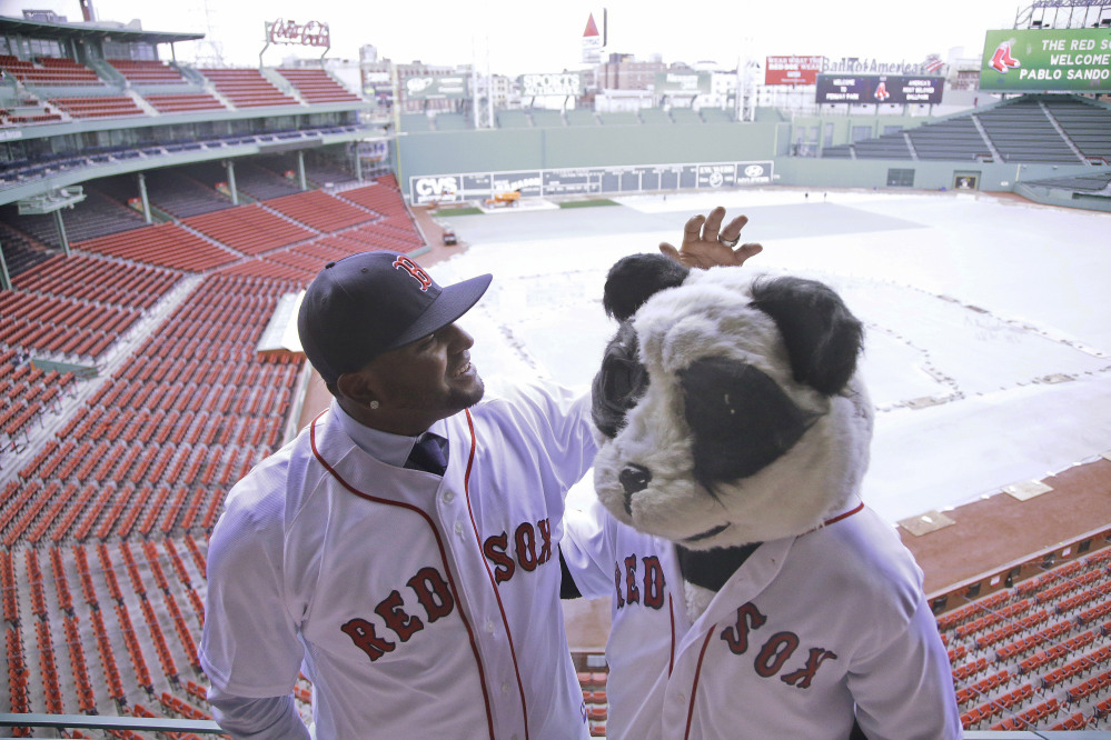 Newly acquired Boston Red Sox free agent third baseman Pablo Sandoval, nicknamed Kung Fu Panda, converses with a person dressed as a panda bear wearing a Red Sox jersey, overlooking a snow covered  Fenway Park field Tuesday in Boston.