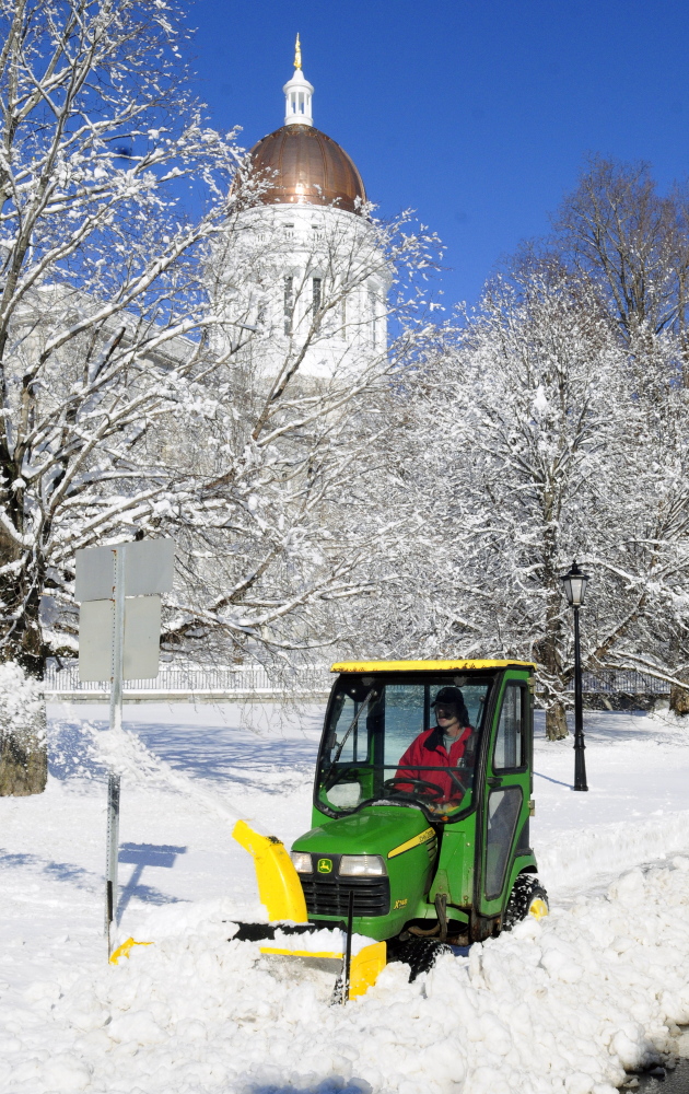 Richard Lachance Jr. runs a tractor with a snowblower along sidewalk in front the State House on Thursday after an overnight snowstorm in Augusta. He and other Bureau of General Services workers spent their Thanksgiving mornings clearing snow from around state government buildings.