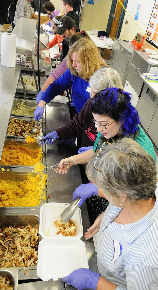 Volunteers serve up food into take-out boxes that were to be delivered at a community Thanksgiving dinner Thursday at Gardiner Area High School.