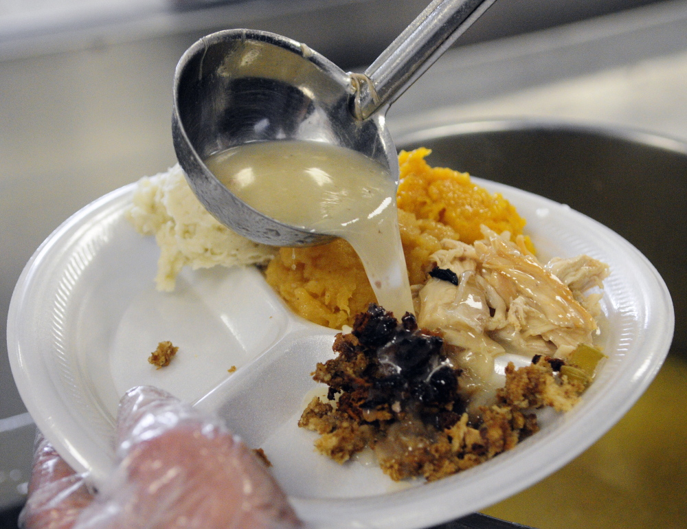 Volunteer David Weinstein ladles gravy onto a plate Thursday during a community Thanksgiving dinner at Gardiner Area High School.