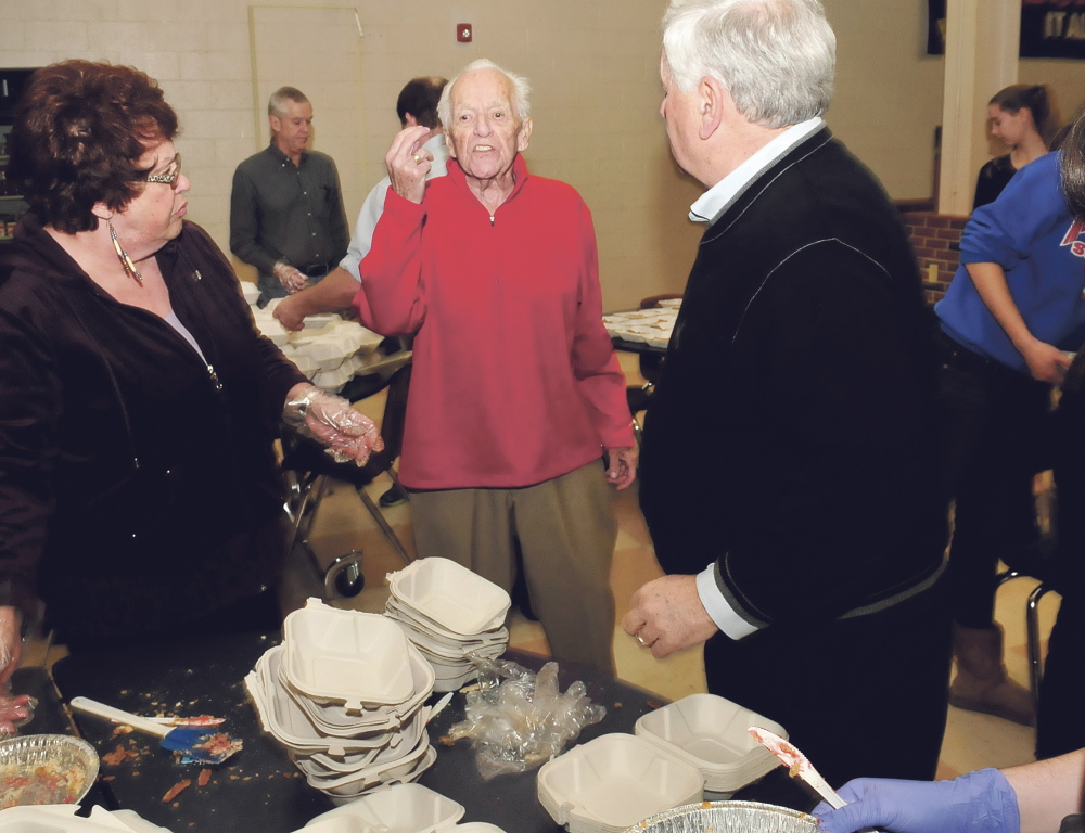 Bud King, center, speaks with volunteers preparing meals Thursday during the annual Thanksgiving dinner at Messalonskee High School in Oakland. King founded the meal 25 years ago. He was quick to credit the scores of volunteers who help make the dinner a continuing success.