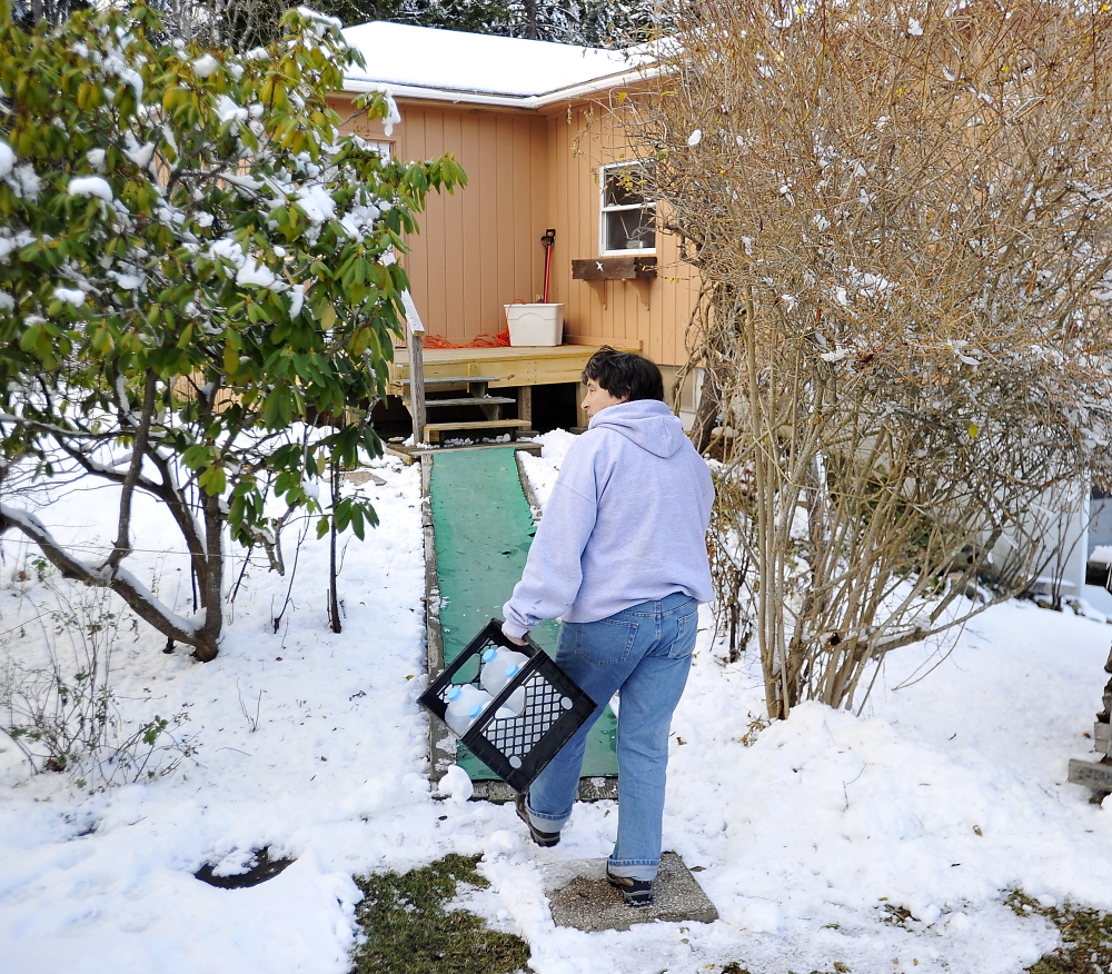 HARPSWELL, ME - NOVEMBER 28: Washburn Road resident Cynthia Forsyth carries  jugs of water from a nearby spring to help with the lack of electricity that usually run the pumps for her normal water supply. (Photo by Gordon Chibroski/Staff Photographer)