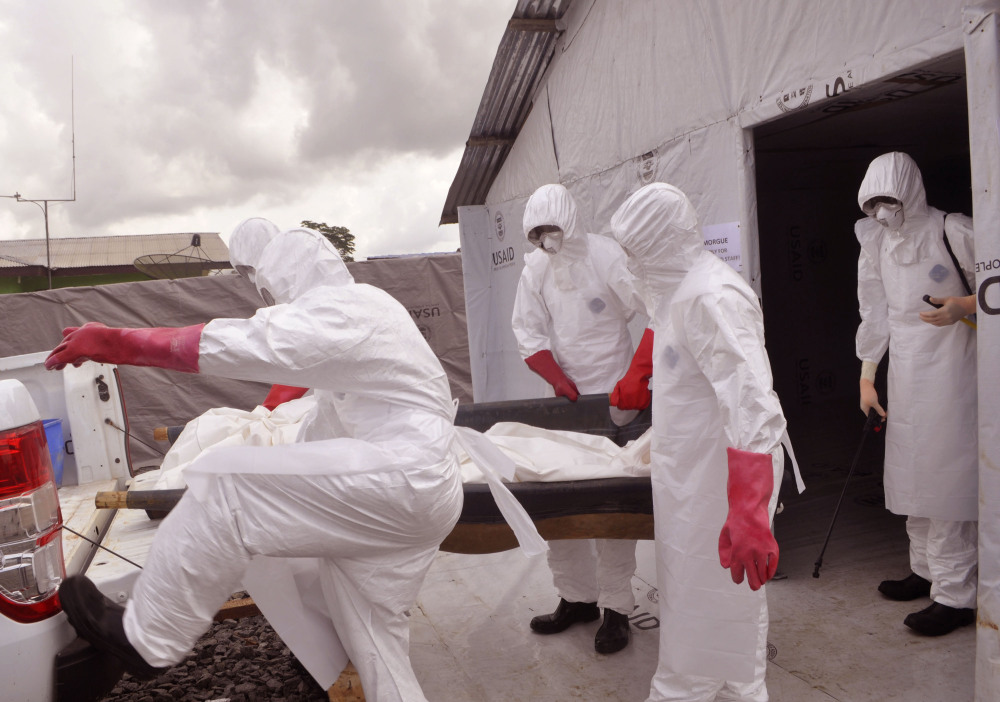 Health workers wearing Ebola protective gear remove the body of a man they suspect died from the Ebola virus, at a USAID, American aid Ebola treatment center at Tubmanburg on the outskirts of  Monrovia, Liberia.