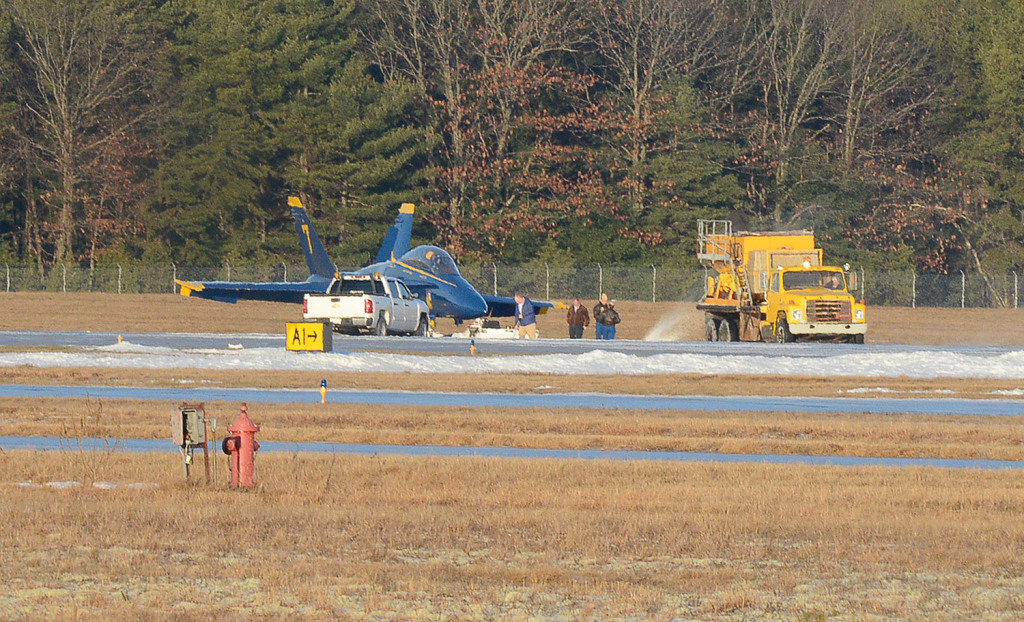 Ice melting product is spread by a crew after Blue Angels #7, flown by Capt. Jeff Kuss and Corrie Mayes, slid off the runway after landing at the Brunswick Executive Airport Thursday. John Patriquin/Staff Photographer