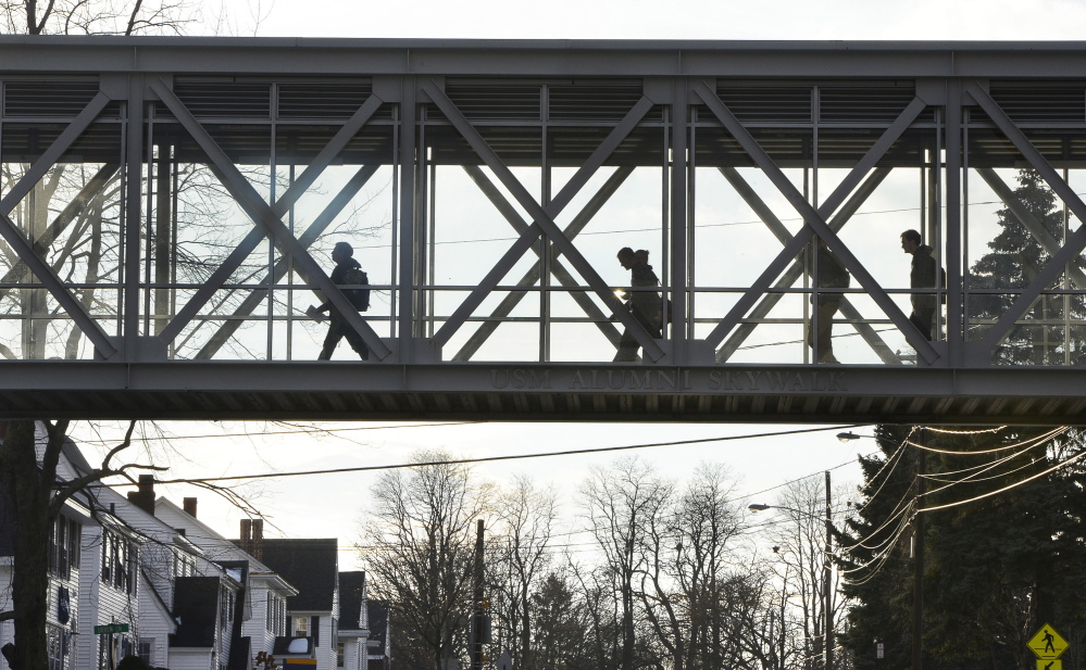Students cross the USM Alumni Skywalk on the campus in Portland on Monday. Faculty members and students have decried the cuts at the university, saying they go too far.