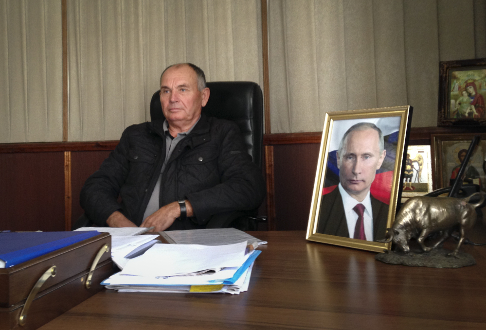 In this photo taken on Wednesday, Oct.  22, 2014, quail egg farmer Mikhail Sirotyuk speaks to the Associated Press in an interview in Trudovoe, Crimea. Sirotyuk, whose office in the rural village of Trudovoe is decorated with two portraits of Putin and three religious icons, has changed the locks out of fear of what might happen next.