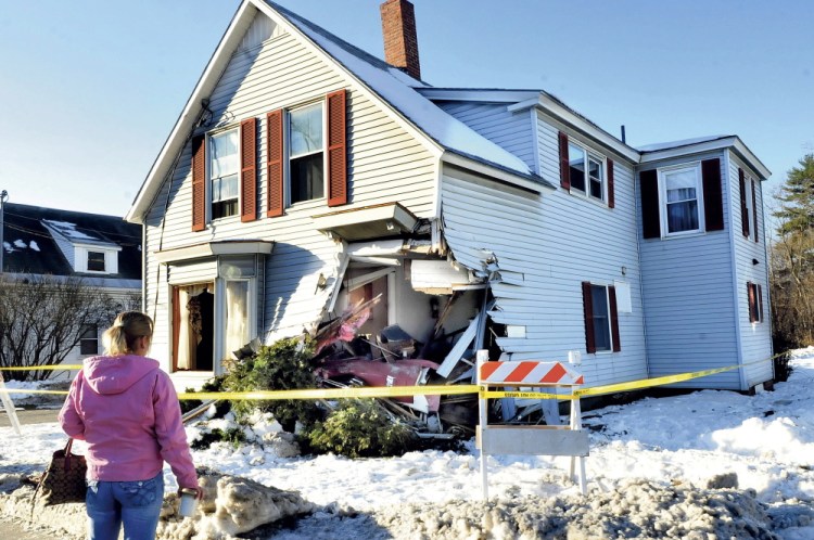 Shannon Thaller, who said she was a housekeeper for the owners of this house, surveys the damage left after a tractor trailer struck the building on Madison Avenue in Skowhegan on Tuesday. The building had a gaping hole in the corner. Thaller said she couldn’t believe the damage and was glad no one was home when the incident occurred.