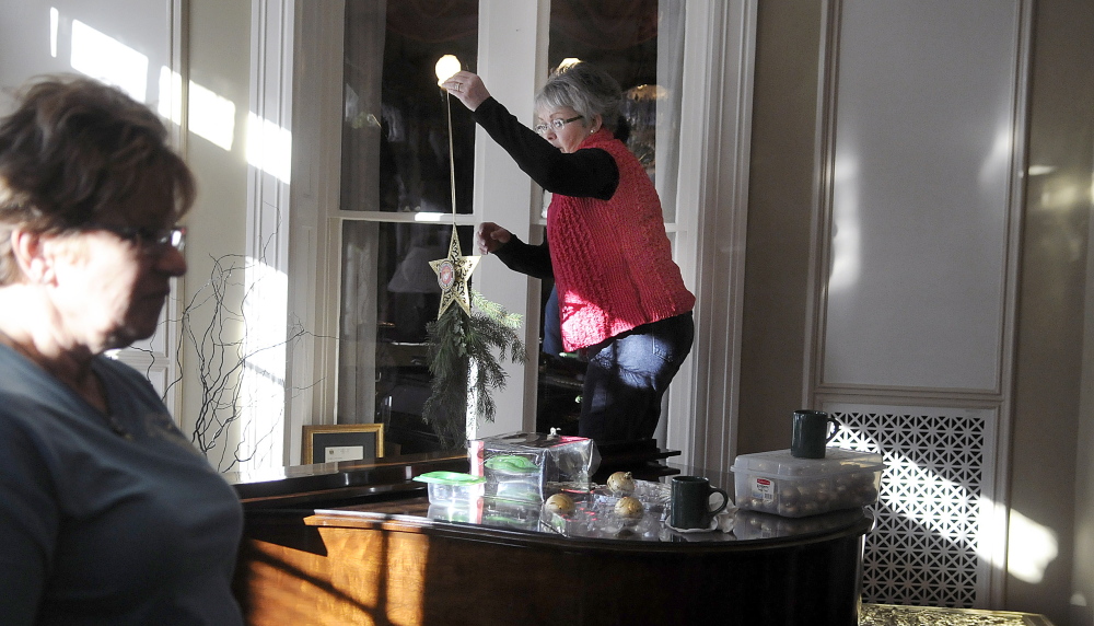 Shelly Hanson, right, and Pam Johnson decorate the Blaine House on Tuesday with other members of the Kennebec Valley Garden Club. The group chose a military theme this year.