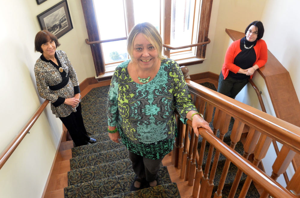 Lee Folsom, head of adult services and circulation, foreground, Catie Carson-Gabriel, back left, resource development coordinator, and Tammy Rabideau, back right, business and career center coordinator, pose for a portrait in the stairwell at the Waterville Public Library on Tuesday.