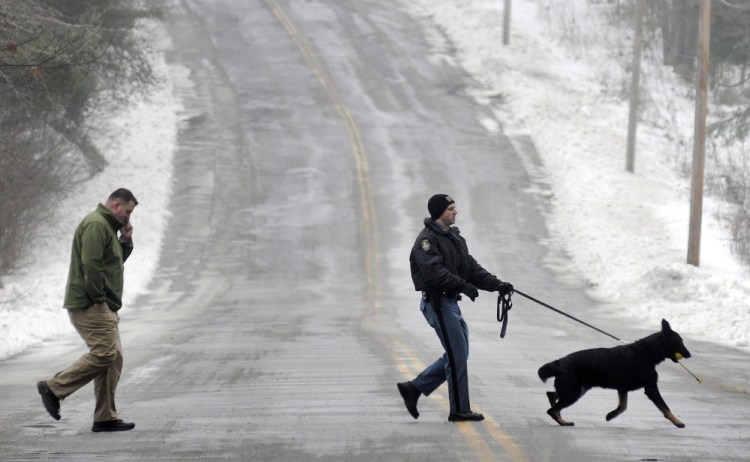 State Trooper G.J. Neagle accompanies his tracking dog with Augusta Police Dept Detective Chris Blodgett while searching Wednesday for a person reported to be in the woods between Farrington Elementary School and Cony High School in Augusta.  Both school were locked down for about an hour while police searched the woods. Nobody was found, according to police. Staff photo by Andy Molloy