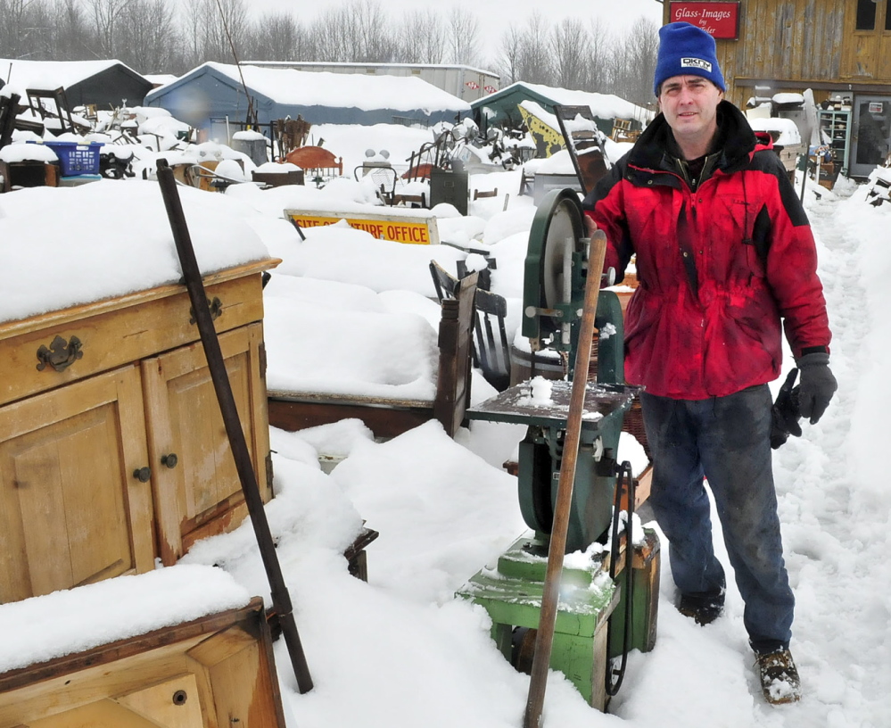 Robert Dale, owner of Maine 201 Antiques, stands in the middle of a sprawling collection of household items, farm equipment, glass and metal items in Fairfield in March. Dale has been ordered to clean up the property, and a judge this week ordered him to pay the town $28,369. He’ll be in court again in January.