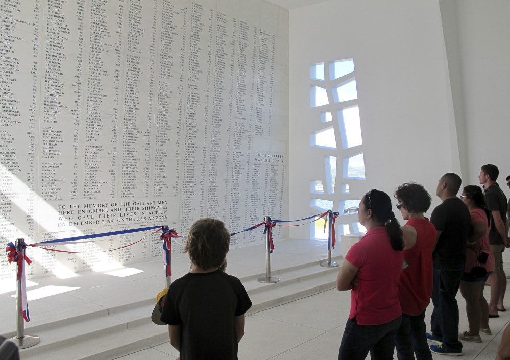 This Nov. 21, 2014 photo shows visitors looking at a wall inscribed with the names of the USS Arizona’s fallen at a memorial for the sunken battleship in Pearl Harbor, Hawaii.