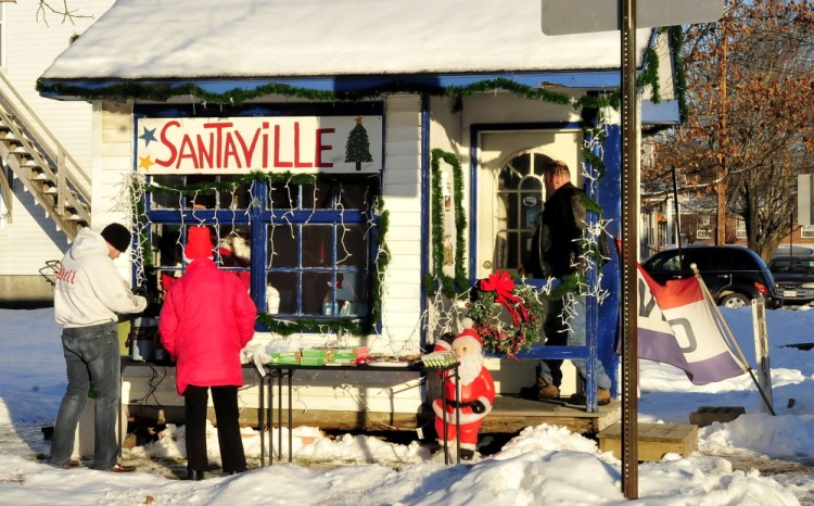 Santa’s helpers, C.J. Duplessie, left, and Tina Worthley, set out treats and hot coffee outside Santaville on Main Street in Madison.