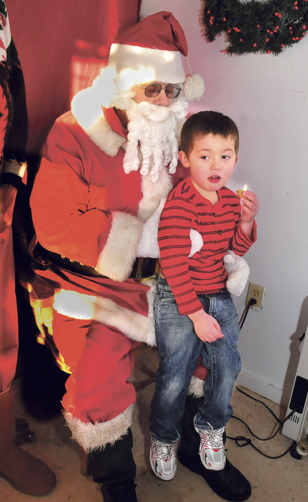 Between bites of a cookie, 3-year-old Sebastion Christie tells Stephen Foshay, dressed as Santa, what he wants for Christmas at the new location of Santaville in downtown Madison.