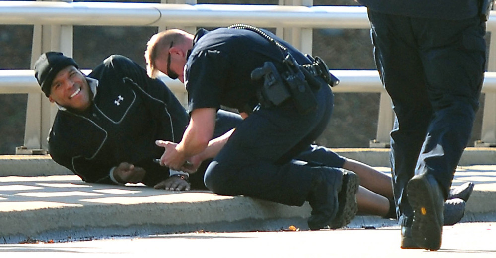 A Charlotte-Mecklenburg police officer tends to Carolina Panthers NFL football quarterback Cam Newton following a two-vehicle crash not far from the team’s stadium in Charlotte, N.C., Tuesday.