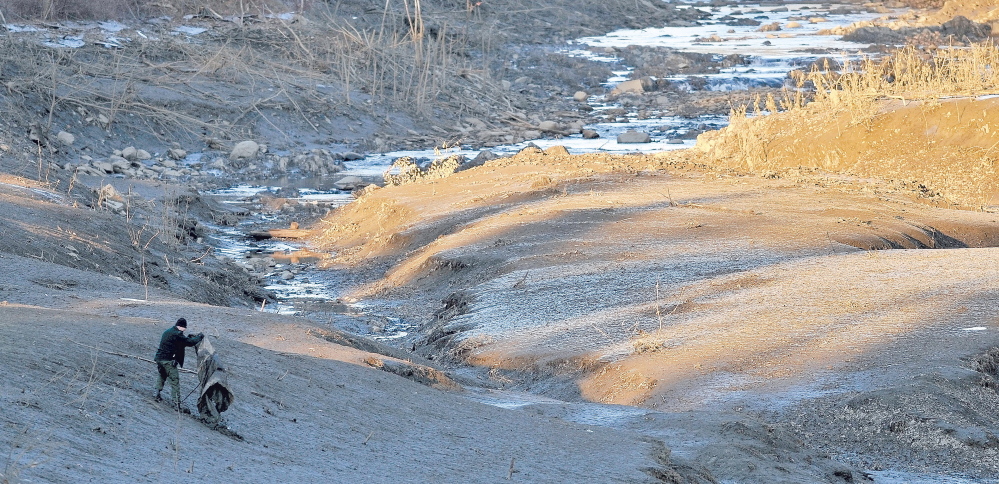 A searcher scours the emptied river bed of the Messalonskee Stream along West River Road near the intersection of Kennedy Memorial Drive in Waterville Dec. 20, 2011, afternoon for a missing 20 month old girl.