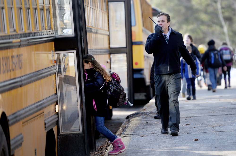 Windham Primary School Principal Kyle Rhoads talks on a radio as students board buses Monday,