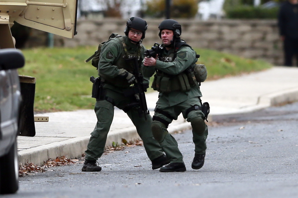 Police move near the scene of a shooting Monday, in Souderton, Pa. Police are surrounding a home in Souderton, outside Philadelphia, where a suspect is believed to have barricaded himself after shootings at multiple homes.