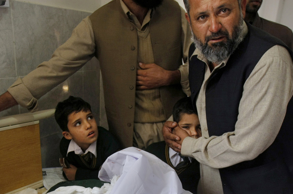 A Pakistani man comforts a student standing at the bedside of a boy who was injured in a Taliban attack on a school, at a local hospital in Peshawar, Pakistan, Tuesday, Dec. 16, 2014. Taliban gunmen stormed a military-run school in the northwestern Pakistani city of Peshawar on Tuesday, killing more than 100, officials said, in the worst attack to hit the country in over a year.(AP Photo/Mohammad Sajjad)