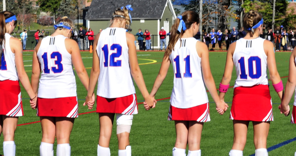 In a sign of respect and support, members of the Messalonskee field hockey team hold hands Oct. 13 during a moment of silence for student and soccer player Cassidy Charette, who died Oct. 11 in a hayride accident in Mechanic Falls.