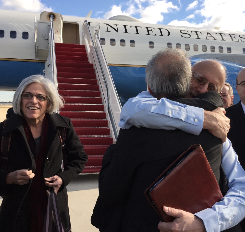 In this handout photo provided by Jill Zuckman, Alan Gross, facing camera, is hugged by Tim Rieser, an aide to Sen. Patrick Leahy, D-Vt., Wednesday, Dec. 17, 2014, at Andrews Air Force Base, Md., upon his arrival from Cuba. Gross's wife Judy is at left, Rep. Jim McGovern, D-Mass. is at right. (AP Photo/Jill Zuckman)
