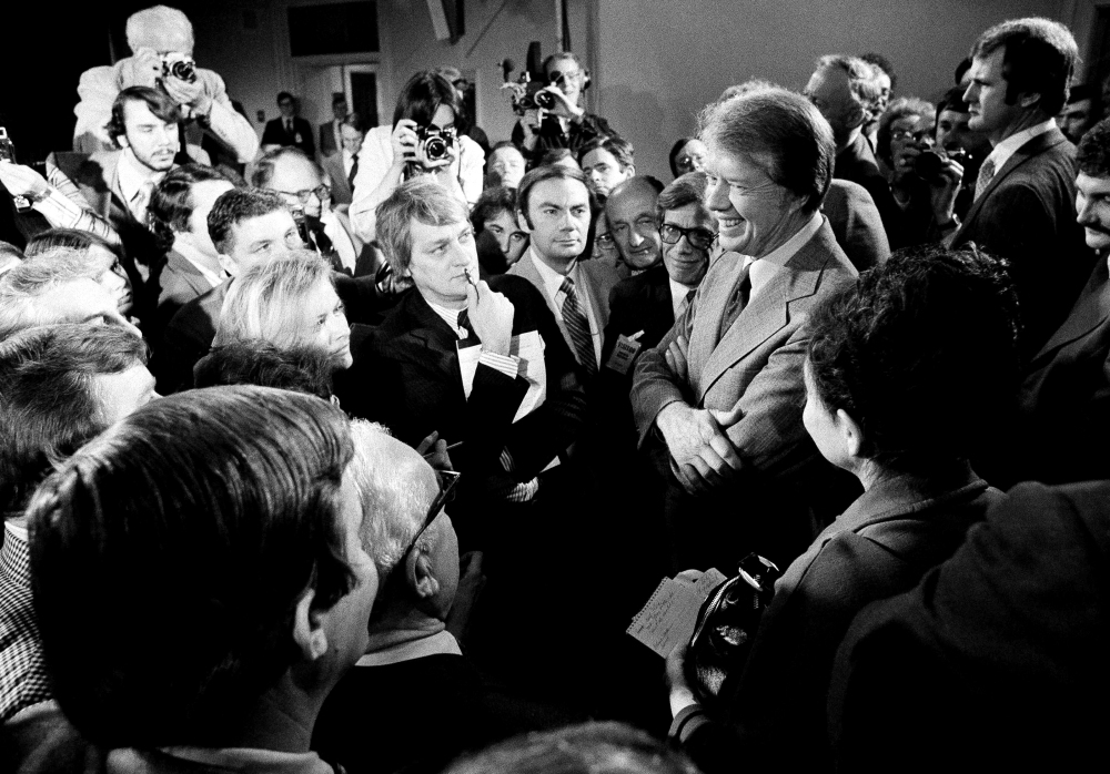 FILE - In this March 9, 1977 file photo, President Jimmy Carter, right, is surrounded by journalists after a news conference where he announced the lifting of the travel ban on Cuba, Vietnam, North Korea and Cambodia, in the executive office building in Washington, D.C. Carter tried to normalize relations with Cuba shortly after taking office in 1977, re-establishing diplomatic missions and negotiating release of thousands of prisoners. But conflicts over Cuba's military mission in Africa, tension caused by a flood of Cuban refugees in 1980 and the election of Ronald Reagan end the rapprochement. On Wednesday, Dec. 17, 2014, the U.S. and Cuba agreed to re-establish diplomatic relations and open economic and travel ties, marking a historic shift in U.S. policy toward the communist island after a half-century of enmity dating back to the Cold War. (AP Photo, File)